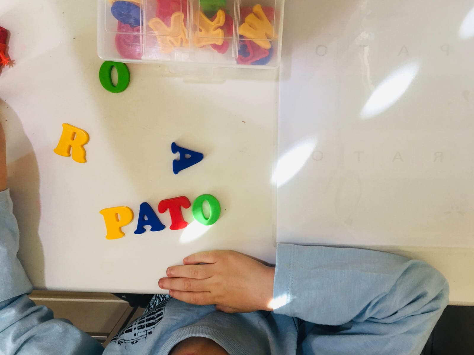 Criança formando a palavra pato com letras móveis coloridas