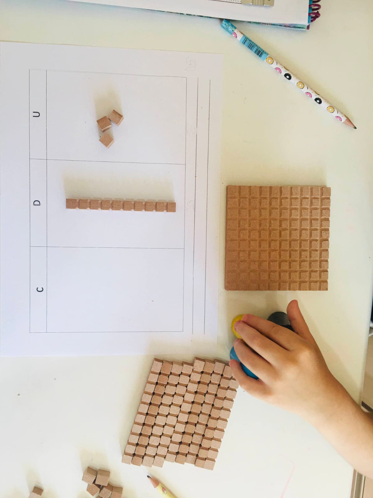 Atividade de matemática com material dourado para representar unidades, dezenas e centenas